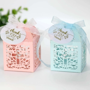 Detail van lasergesneden holle kruis snoepdozen in roze en blauw met linten en labels