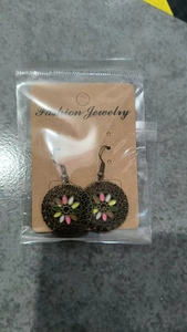 Close-up of vintage floral hollow-out earrings with colorful enamel in retail packaging