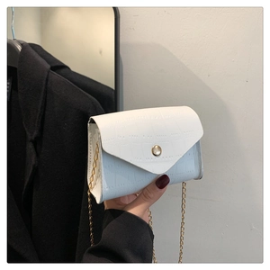Close-up of white crocodile pattern shoulder bag with gold chain and metal buckle detail