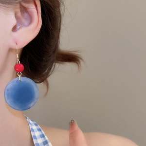 Gros plan de boucles d'oreilles géométriques en acrylique bleu et perles rouges vintage