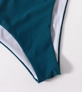 Close-up of teal bikini stitching and dual-layer fabric texture on a white background