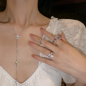 Detailed view of silver bow-shaped rings and Y-shaped tassel necklace with zircon stones