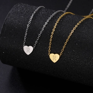 Macro detail of gold and silver heart pendants featuring letter R on cable chains