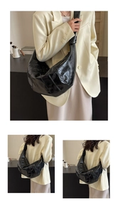 Detail shot of black crescent croissant bag with pleated texture and adjustable strap