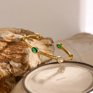 Detail of 18k gold plated stainless steel cuff with emerald stones and hammered texture
