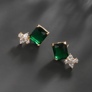 Macro detail of rectangle emerald cut green gemstone and white zircon flower earrings