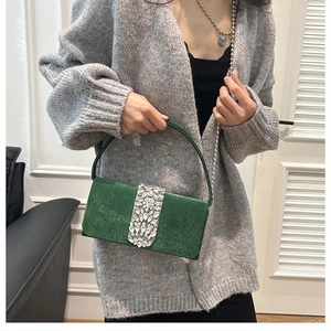 Detail of dark green velvet evening bag featuring rhinestone clasp and silver bead chain