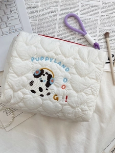 Cute puppy embroidery makeup bag with heart quilting and blue Puppyland text on a desk