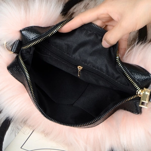 Detail view of the black tote bag interior featuring gold zipper and pink faux fur trim