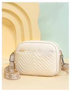 Dettaglio della borsa a tracolla beige in ecopelle con trama litchi e tracolla decorata