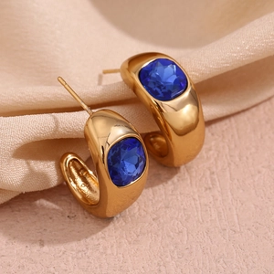 Detailed close-up of vintage C-shaped gold-plated earrings with inset square blue crystals