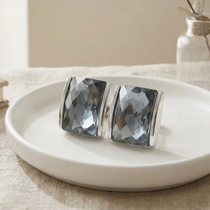 Detailed view of silver rectangular cufflinks with faceted grey crystals on white plate