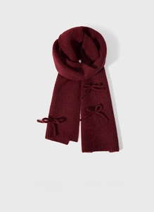 Macro detail of wine red wool blend knit scarf featuring a handmade bow and ribbed texture