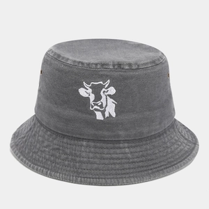 Detail of dark grey washed denim bucket hat featuring white cow embroidery and metal eyelets