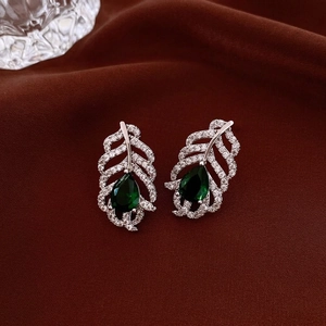 Silver leaf earrings with pear-cut green stones and cubic zirconia on red silk fabric
