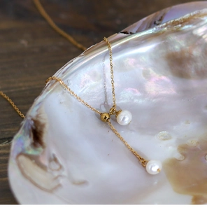 Detailed close-up of natural freshwater pearls on a golden adjustable chain over a shell