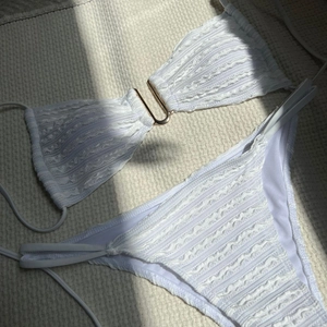 Close-up of white bikini set featuring pleated fabric texture and golden U-shaped buckle