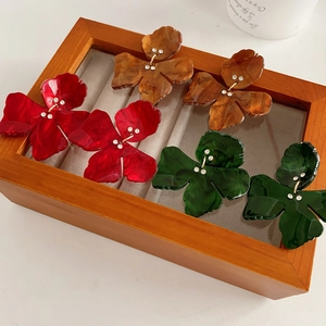 Close-up of resin flower earrings in red, brown, and green with crystal centers in a box