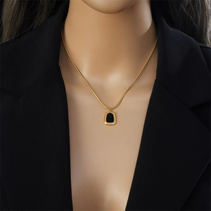 Élégant collier chaîne serpent dorée avec pendentif trapèze noir sur mannequin en costume
