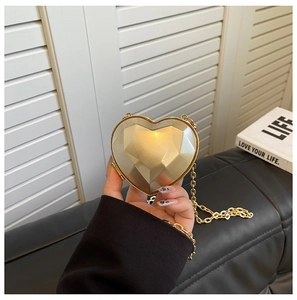 Detailed view of the golden heart-shaped evening bag with a geometric diamond-cut surface