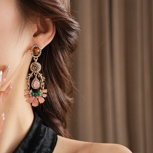Dettaglio di orecchini vintage stile palazzo con gemme rosa a goccia e strass su modella
