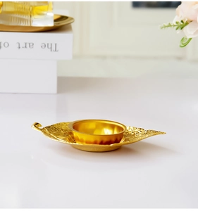 Close-up of golden leaf-shaped metal tray and incense burner bowl on home desk