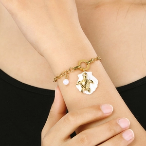 Gold ocean themed titanium bracelet with shell and turtle charms on wrist