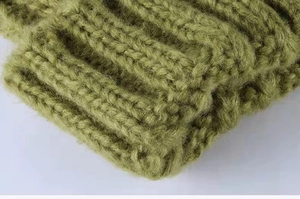 Detailed macro view showing olive green chunky knit texture and soft wool fibers