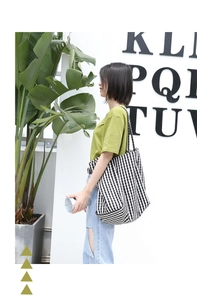 Lifestyle shot of a woman carrying a large black and white checkered canvas tote bag