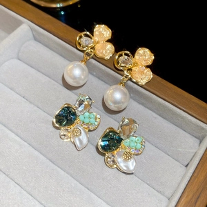 Détail de boucles d'oreilles perles fleurs et puces en cristal émeraude sur velours