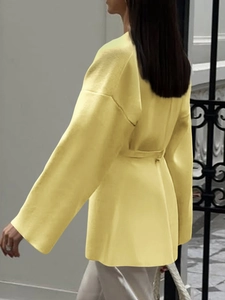 Detail view of yellow long-sleeve knit cardigan with belt shown from a side-back angle