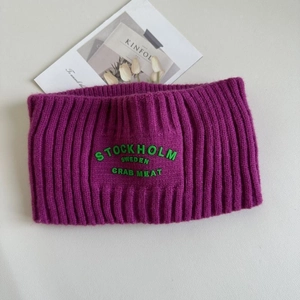 Detail eines lila Strick-Stirnbands mit grünem Stockholm-Schriftzug für Damen