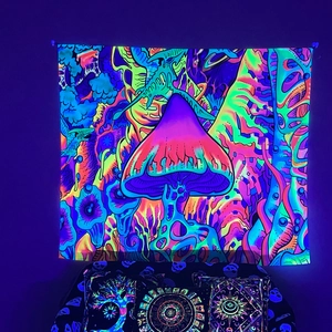 Close-up of UV blacklight reactive tapestry featuring neon glowing psychedelic mushrooms