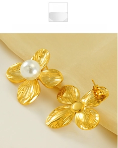 Detail of vintage gold flower petal earrings with white pearl on yellow silk background