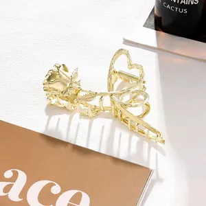 Detailed view of elegant gold metal rose and heart shaped hair claw clip on leather