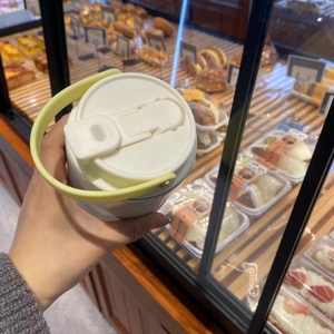 Close-up of white insulated 30oz tumbler with light green handle in a bakery setting
