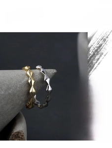 Detail view of gold and silver rhombus geometric rings on a stone display stand