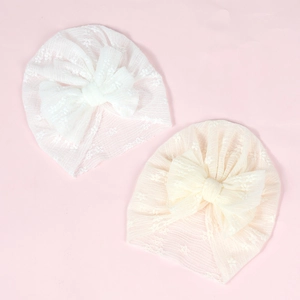 Detailed close-up of breathable white and beige lace baby hats with large mesh bows