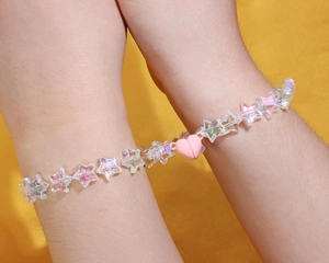 Macro shot of two iridescent star beaded bracelets with a pink heart magnetic clasp