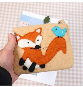 Detail of wool felt coin purse featuring cute embroidered orange fox and blue bird patterns