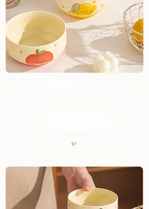 Detail of yellow ceramic fruit bowl with apple and lemon patterns in warm daylight