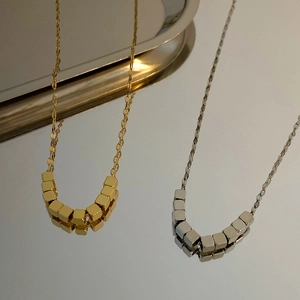 Detailweergave van zilveren en gouden geometrische vierkante kettingen op een spiegel