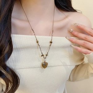 Dettaglio della collana con pendente a cuore in occhio di tigre sul modello stile retrò