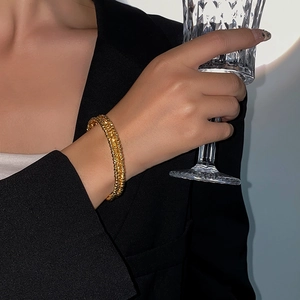 Detail of multi-row gold beaded cuff bracelet on model with elegant metal texture