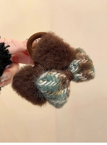 Detail of dark brown plush bow hair clip with green and white plaid fabric texture