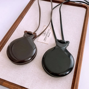 Close-up of elegant coffee and black round mirror pendants on leather necklace cords