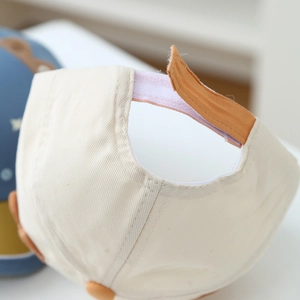 Dettaglio della chiusura a strappo regolabile sul cappellino in cotone per neonati
