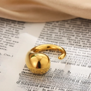 Polished 18K gold water drop knotted open ring displayed on an aesthetic book background