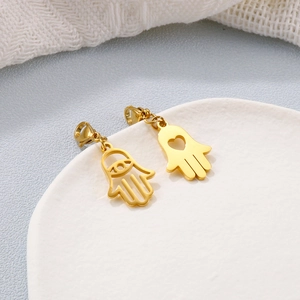 Pendentifs main de Hamsa dorés avec découpes cœur et œil sur plateau blanc