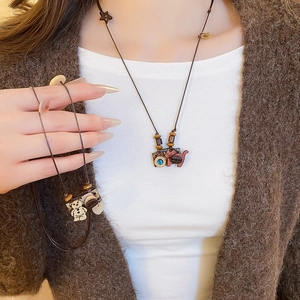 Detail of hand-woven long necklace with wooden beads and cartoon resin cat pendant
